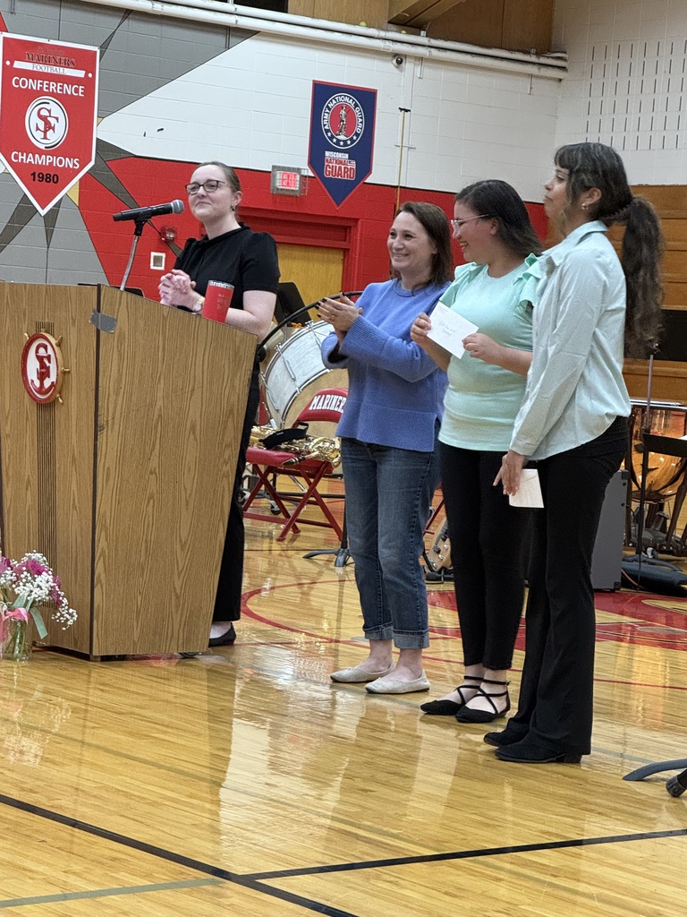One person is behind the podium speaking while three others stand alongside.