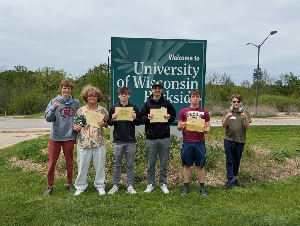 Students stand in front of the Welcome to University of Wisconsin Parksidde sign holding their certificates.