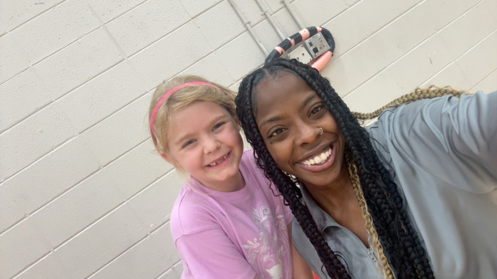 A teacher and student smile for the camera
