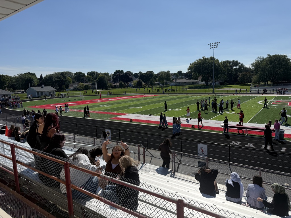 Students on the field with others in the stands.