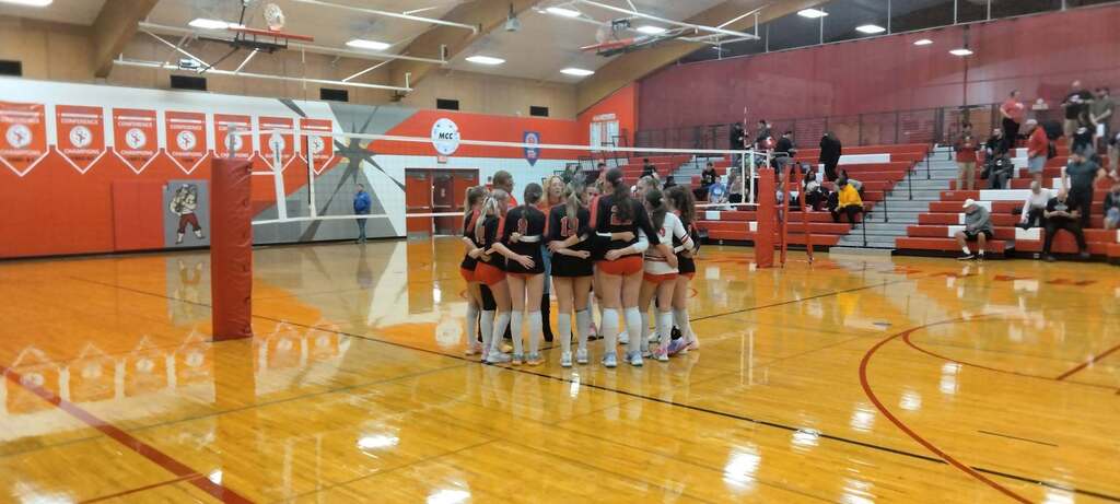Volleyball players huddled on the court.
