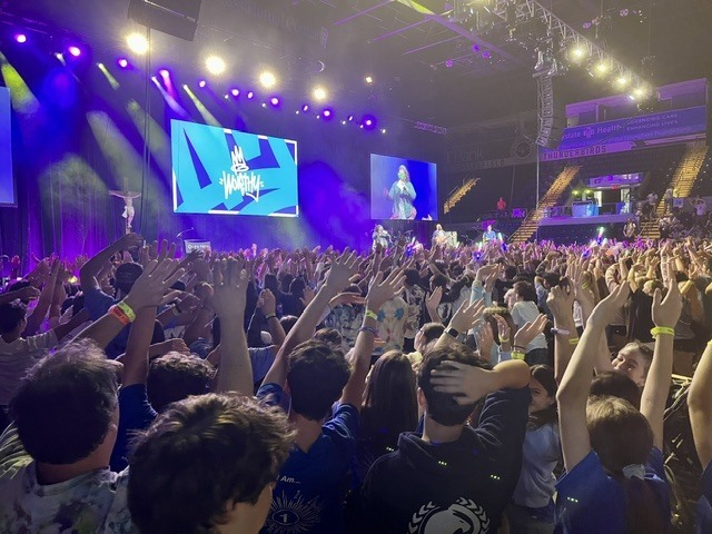 Teens with hands in the air watching performer on stage