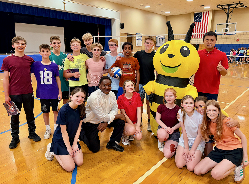 8th grade students with Father Peter and Bee mascot