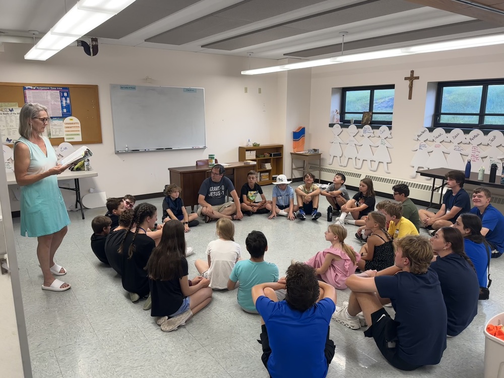 Children in circle listening to catechist at VBS
