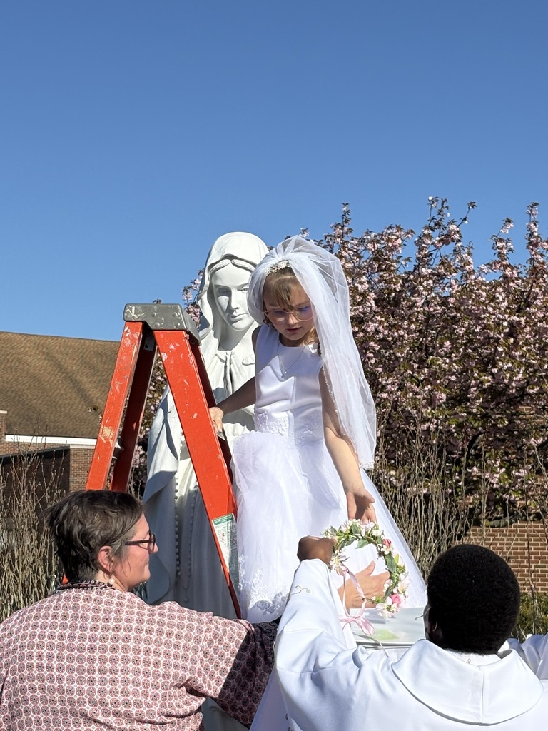 Child crowning statue of Mary with floral crown