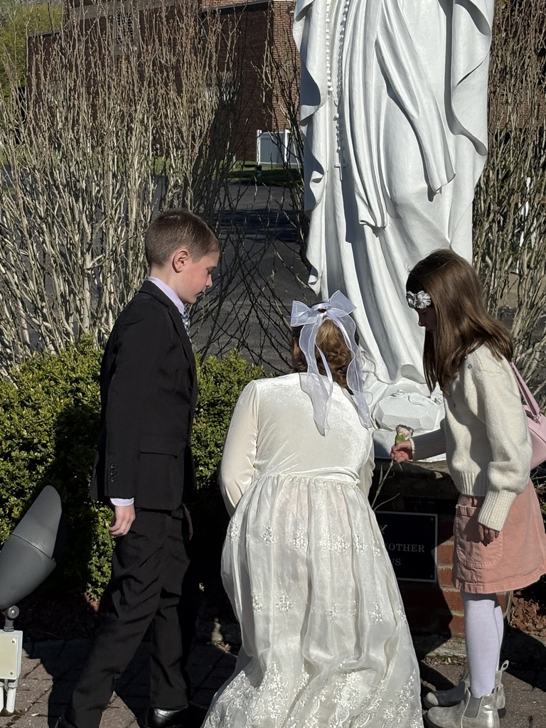 Children placing flowers beneath the statue of Mary on Mother's Day