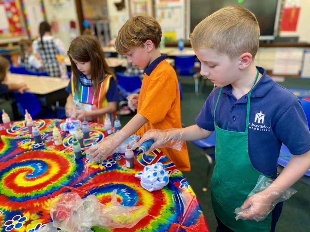 Grade 1 students dye tie-dye t-shirts in their classroom