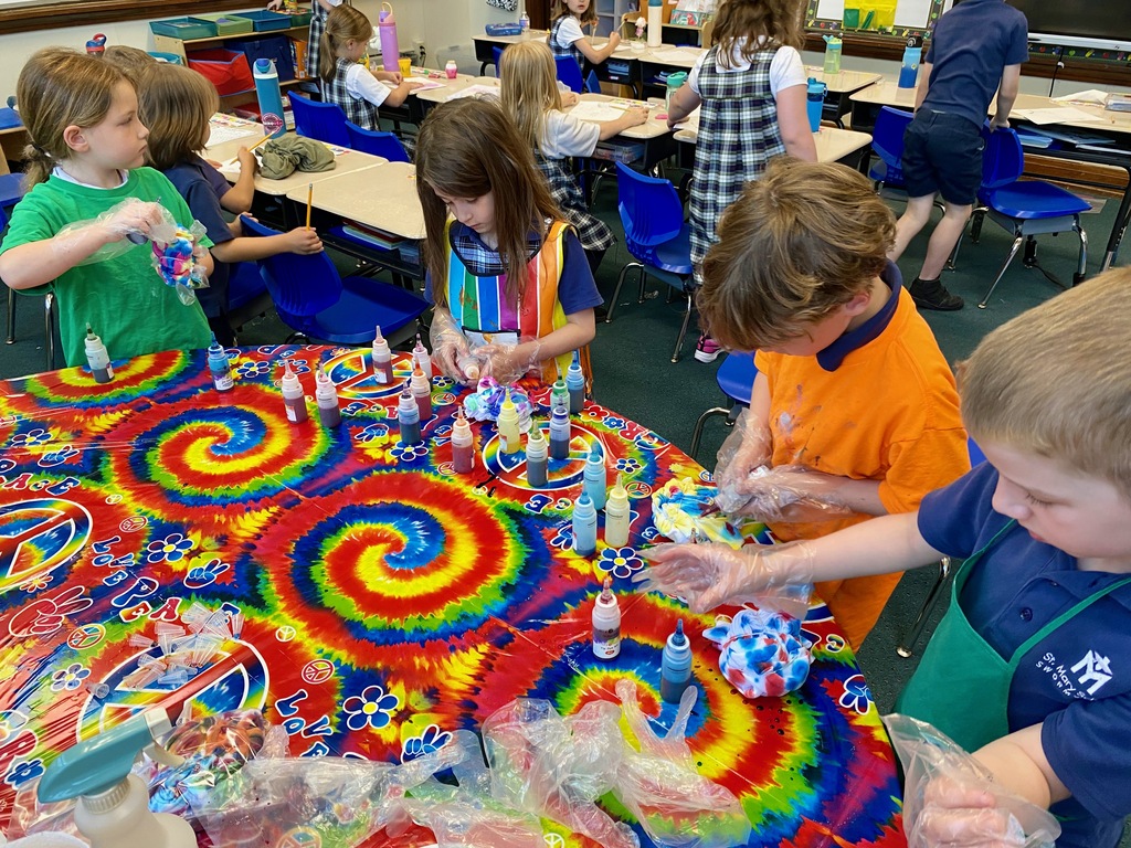 Grade 1 students dye tie-dye t-shirts in their classroom