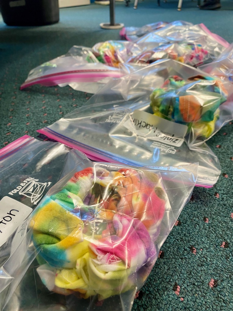 Grade 1 students dye tie-dye t-shirts in their classroom