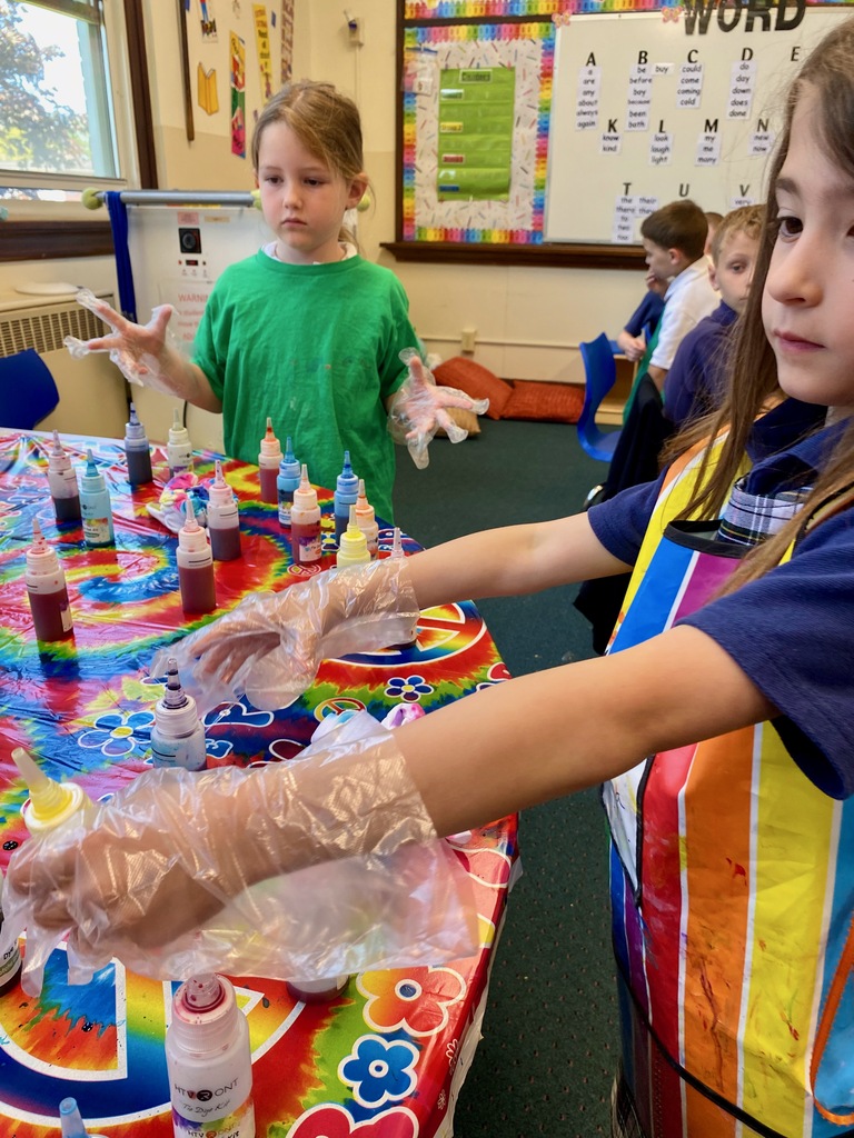 Grade 1 students dye tie-dye t-shirts in their classroom