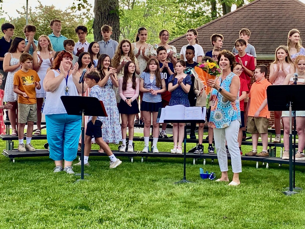 Mrs. Daigler receives a bouquet of flowers from Mrs. D'Angelo in front of the middle school chorus
