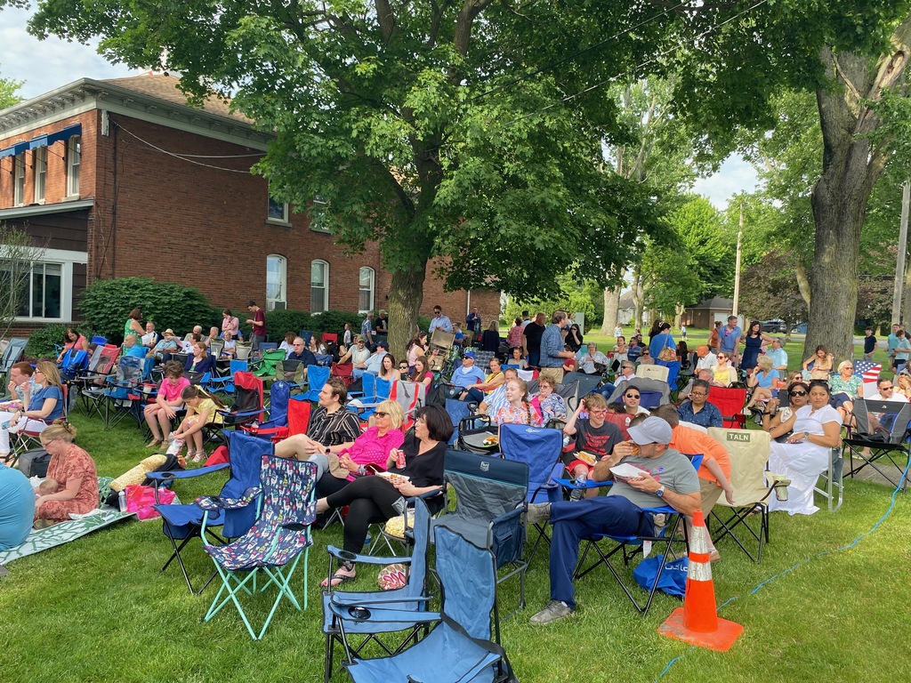 Families in lawn chairs on grass getting ready to watch the concert