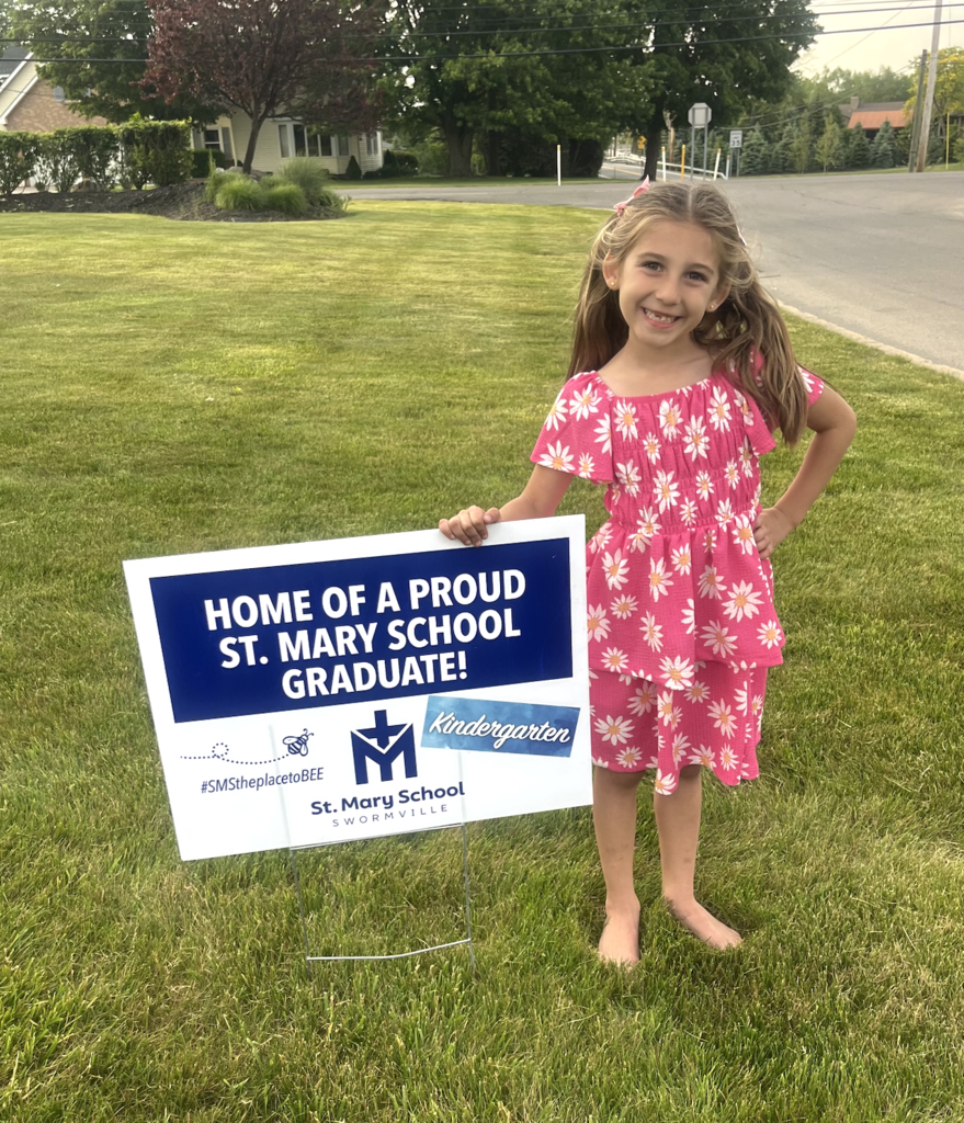 Graduate with lawn sign celebrating their graduation