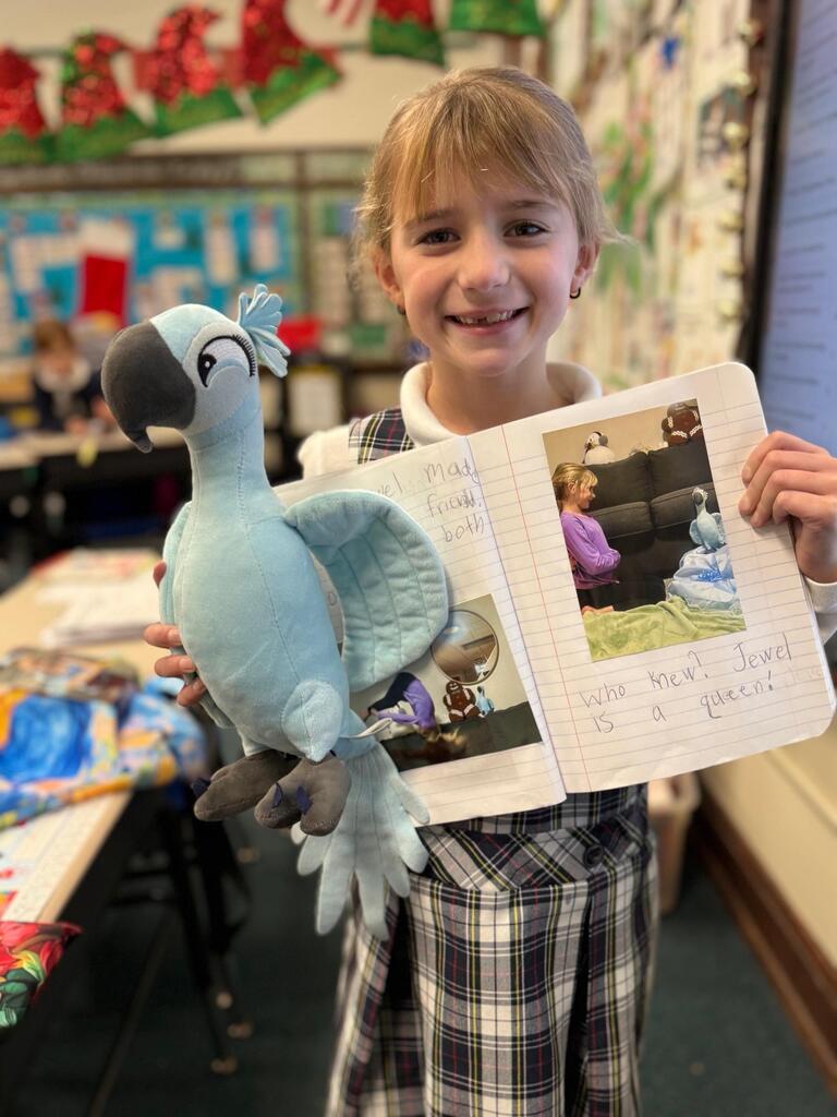 grade 2 student holding a stuffed animal macaw and showing their journal entry