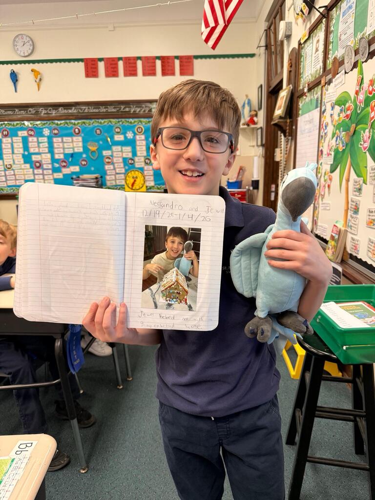 grade 2 student holding a stuffed animal macaw and showing their journal entry