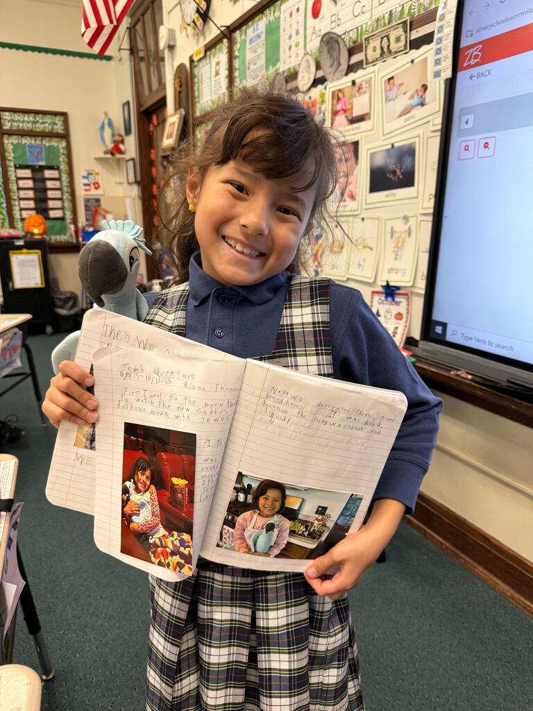 grade 2 student holding a stuffed animal macaw and showing their journal entry