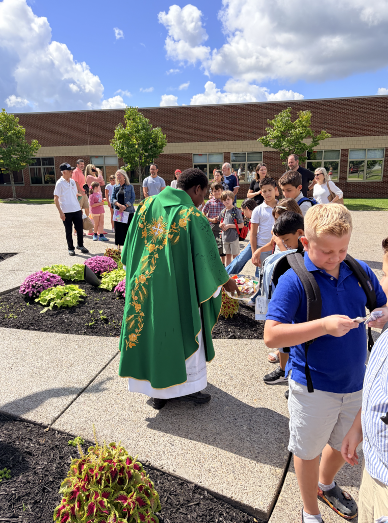 students receiving a back to school blessing outside of Mass before the first day of school