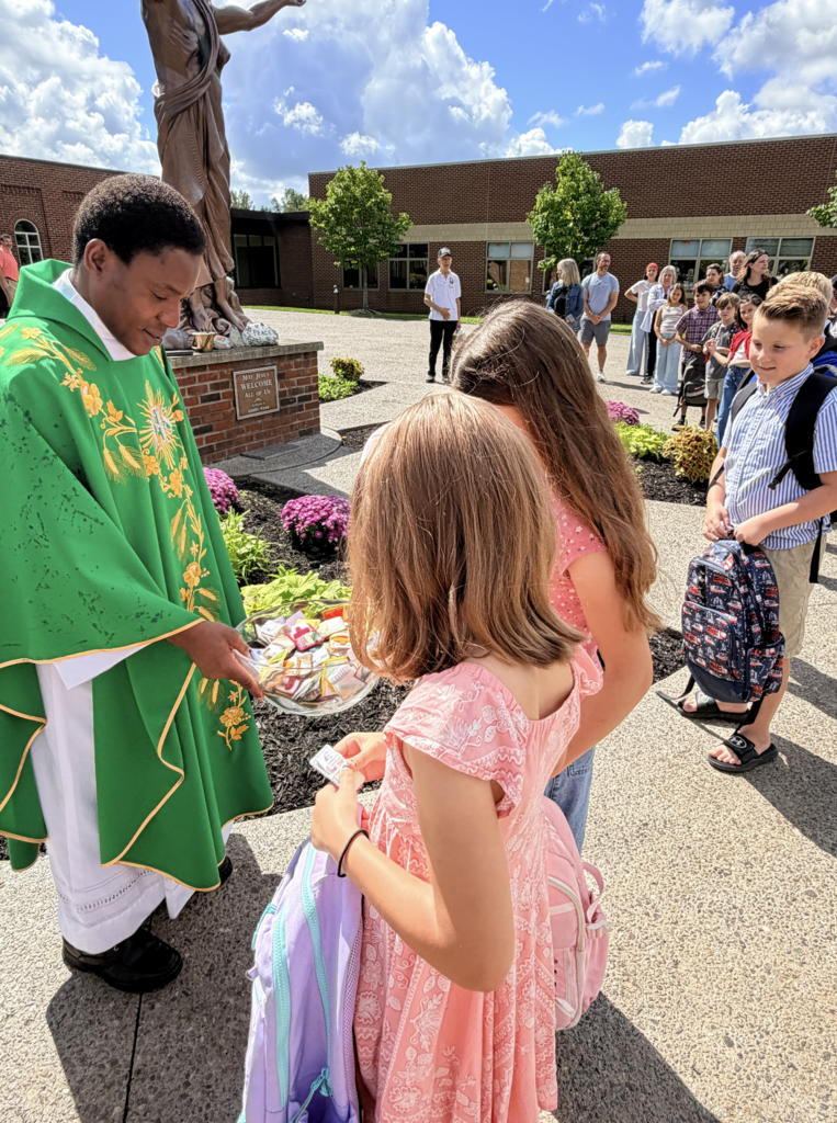 students receiving a back to school blessing outside of Mass before the first day of school