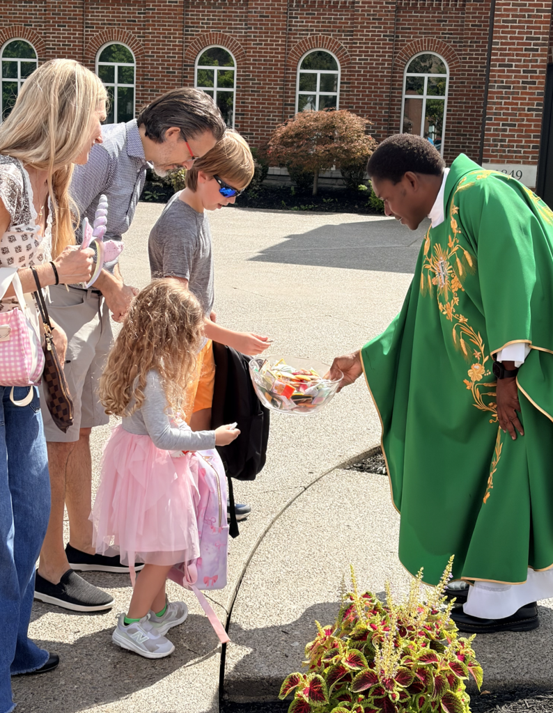 students receiving a back to school blessing outside of Mass before the first day of school