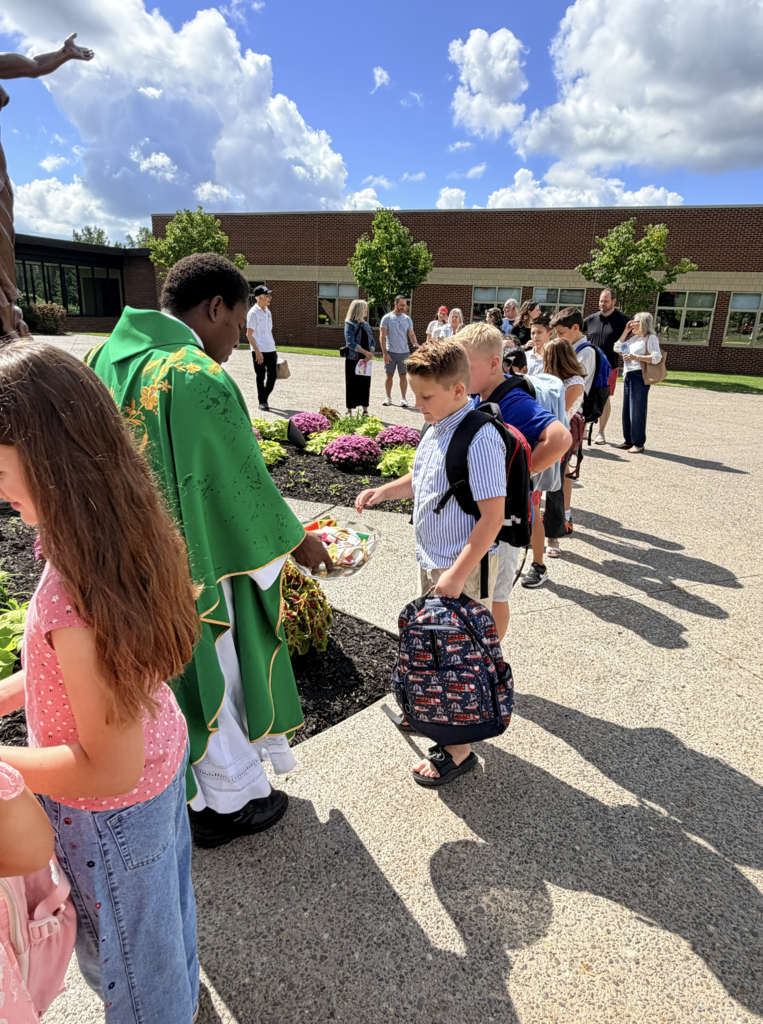 students receiving a back to school blessing outside of Mass before the first day of school