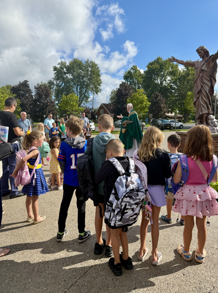 students receiving a back to school blessing outside of Mass before the first day of school