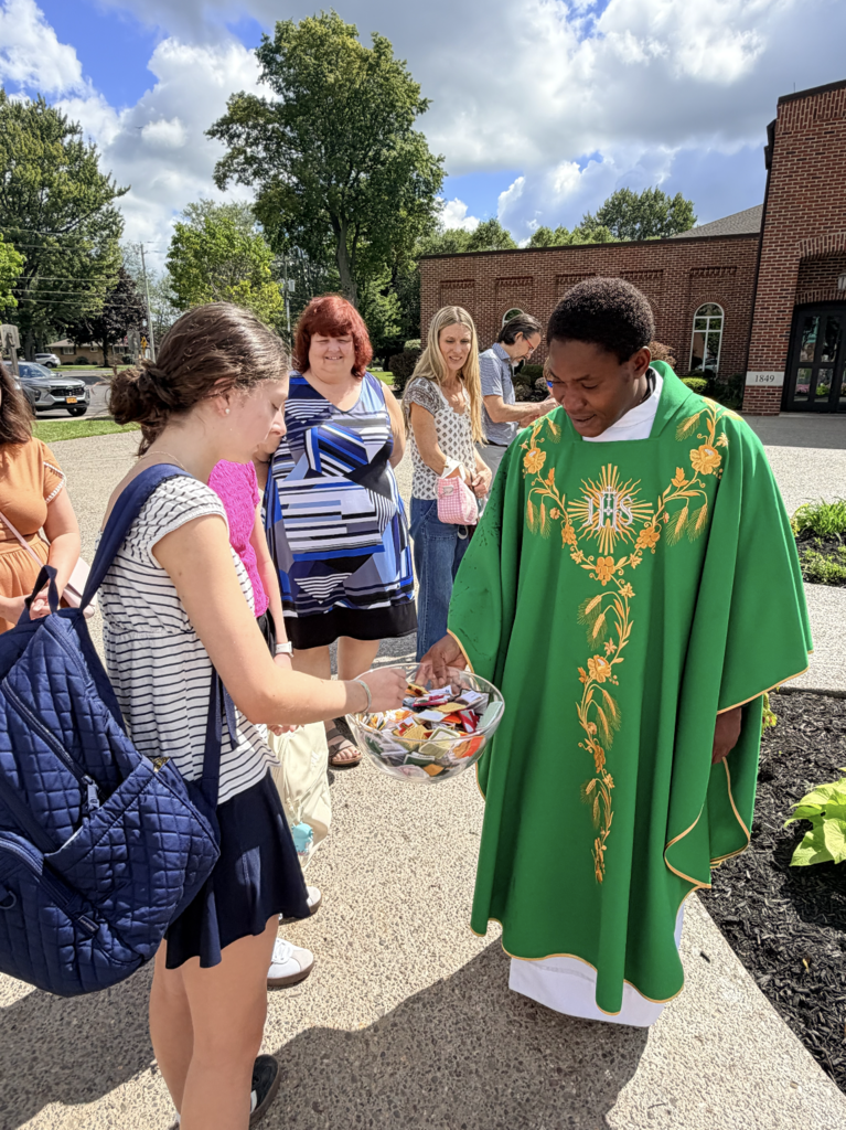 students receiving a back to school blessing outside of Mass before the first day of school