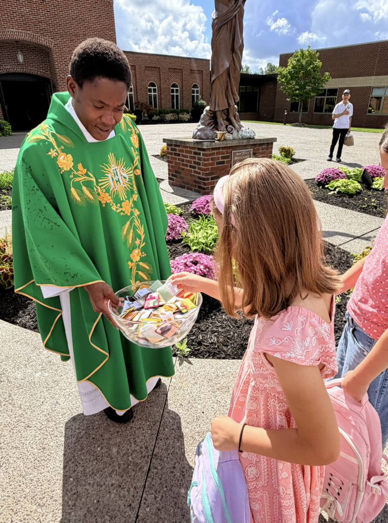 students receiving a back to school blessing outside of Mass before the first day of school