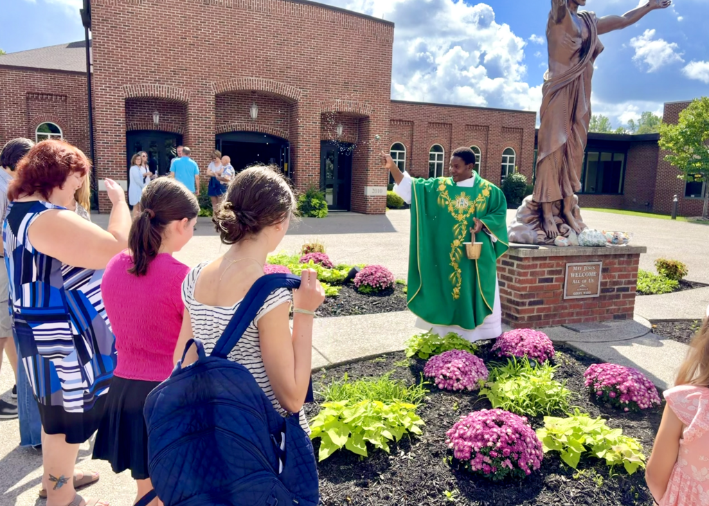 students receiving a back to school blessing outside of Mass before the first day of school