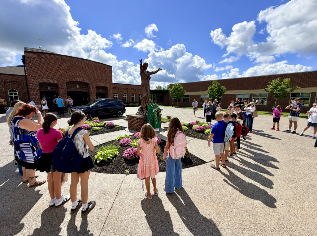 students receiving a back to school blessing outside of Mass before the first day of school