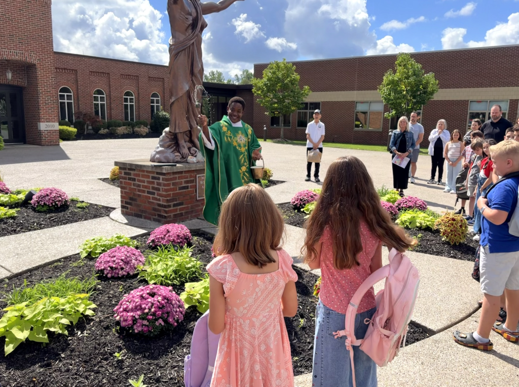 students receiving a back to school blessing outside of Mass before the first day of school
