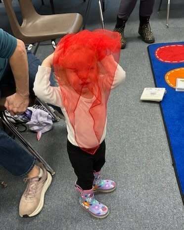 young chiuld playing with a red scarf