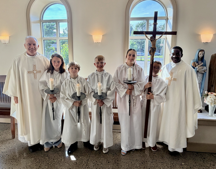 priests with altar servers holding candles and a crucifix