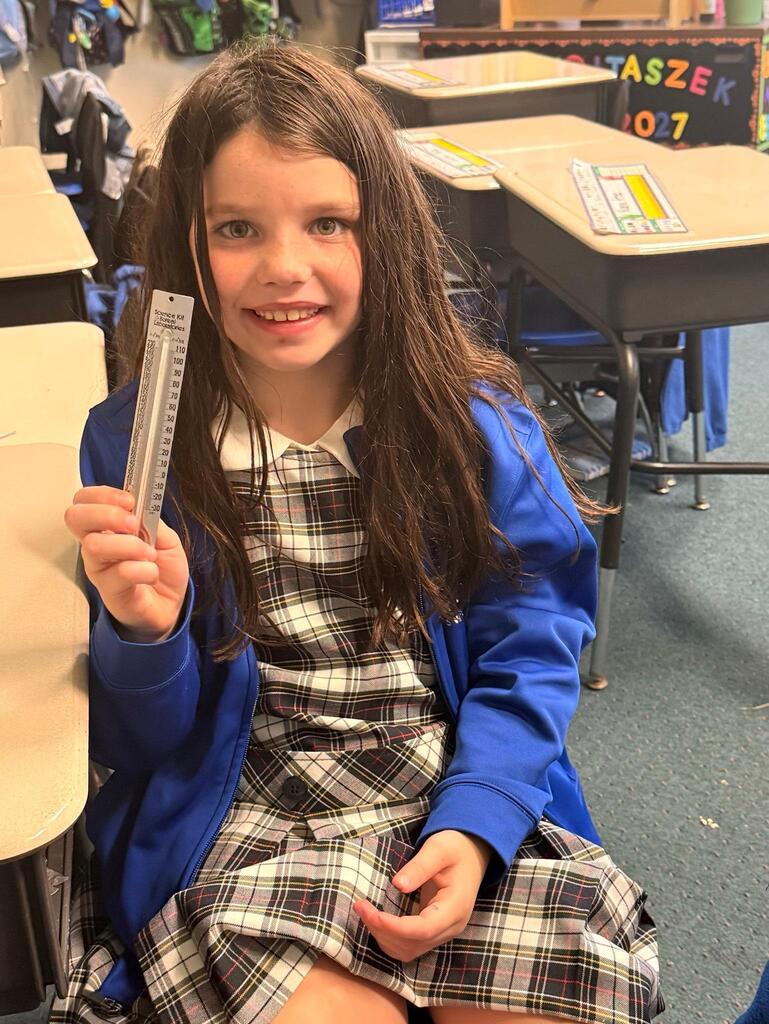 student in grade 2 observing temperature with a thermometer