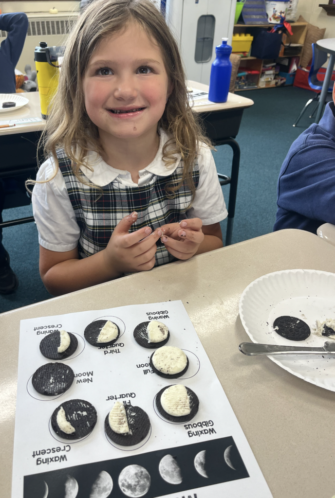 student with moon phases work sheet at desk and oreo cookies