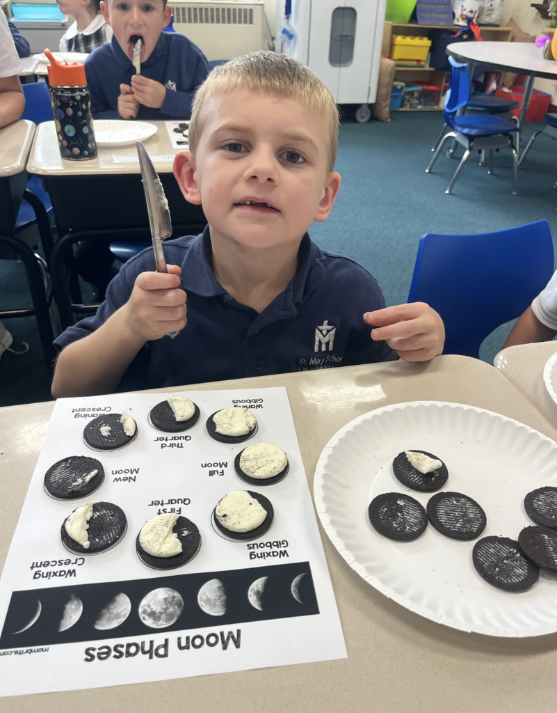 student with moon phases work sheet at desk and oreo cookies