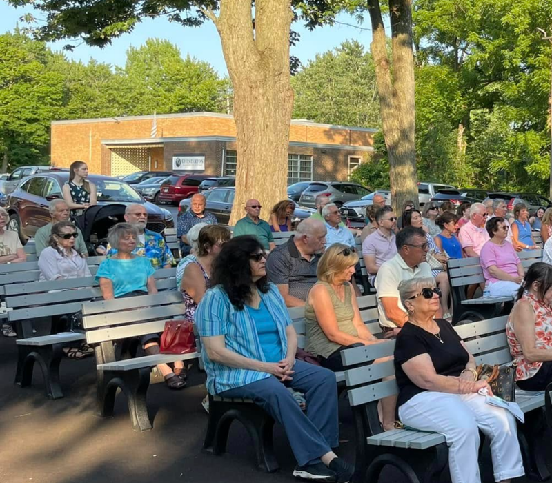 people sitting in outside pews for Mass