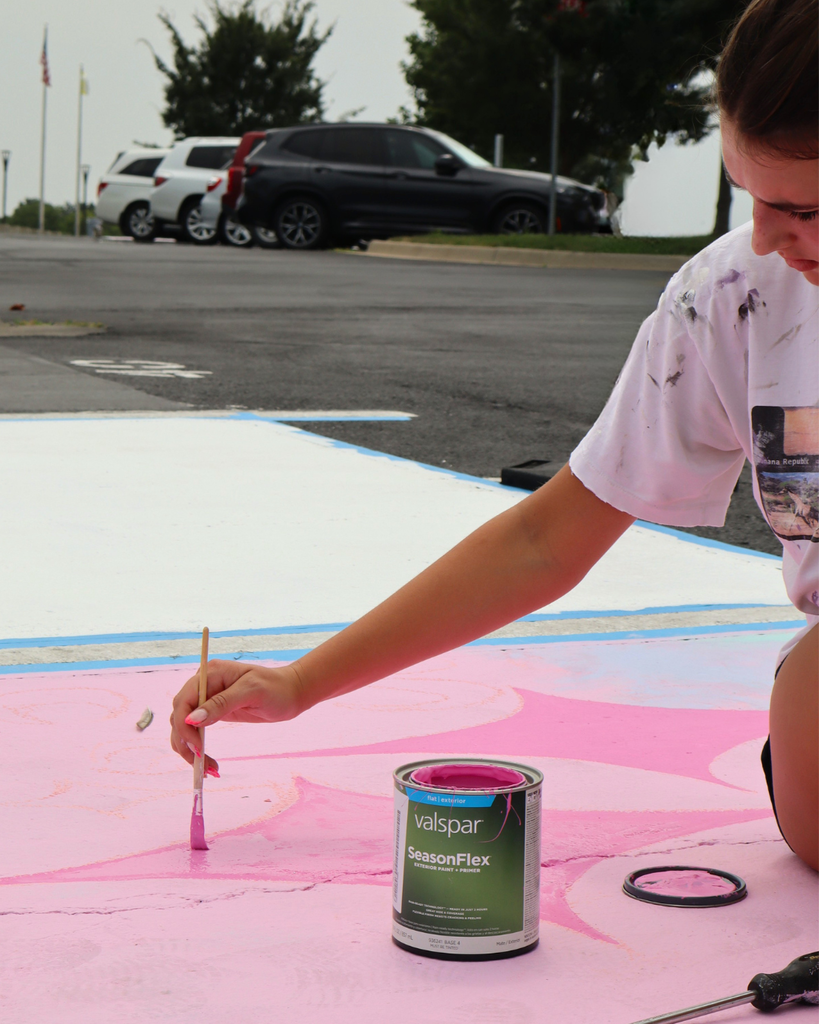 A girl paints her parking spot.