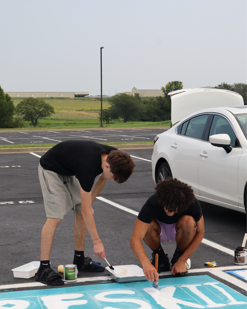 Two boys paint their parking spot.