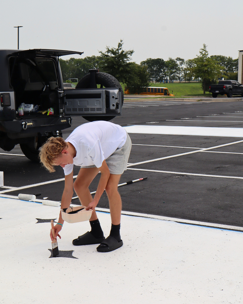 A boy paints his parking spot.