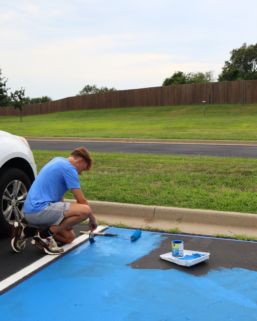 A boy paints his parking spot.