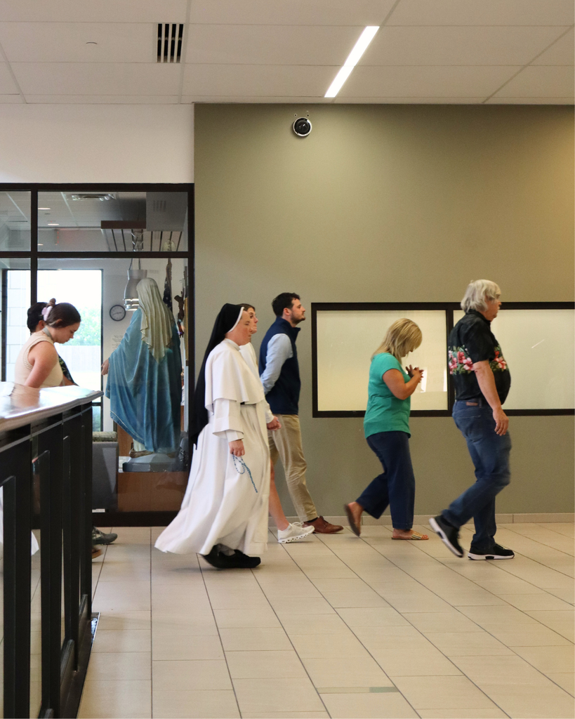 Staff says a rosary in the hall.