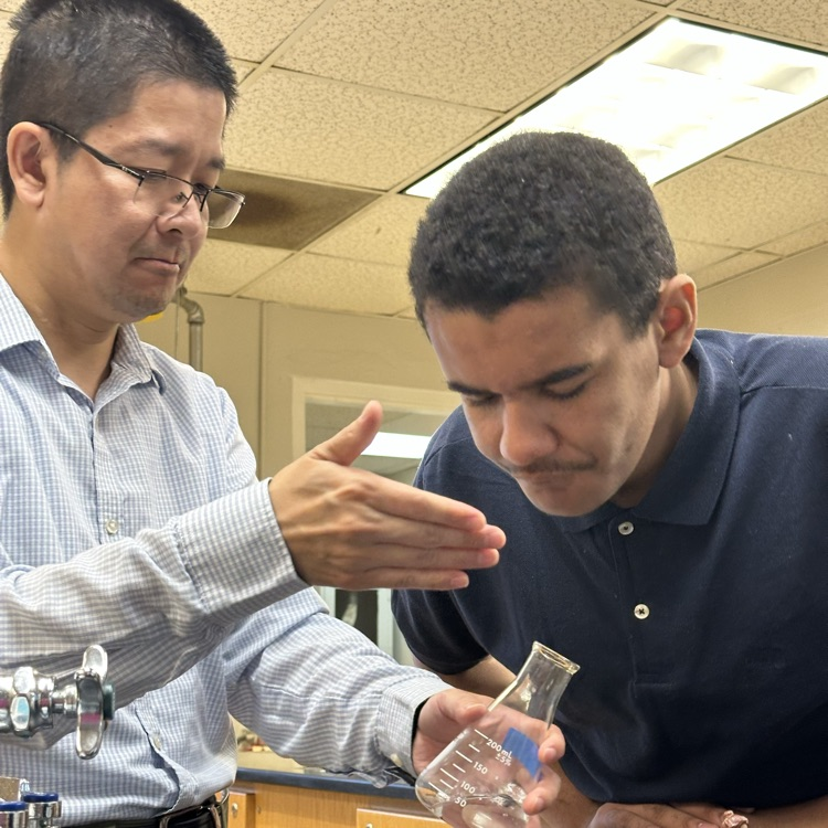 A student is smelling a sample in a Erlenmeyer Flask   