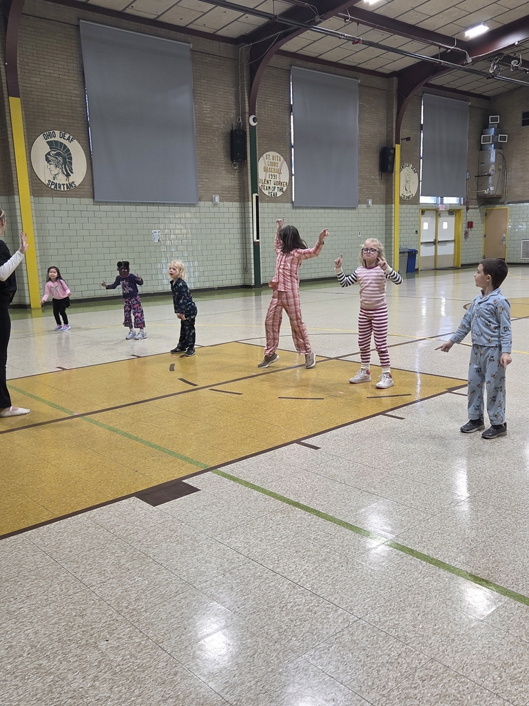 In the gymnasium 6 students are standing in a line dancing and copying the dance teacher.