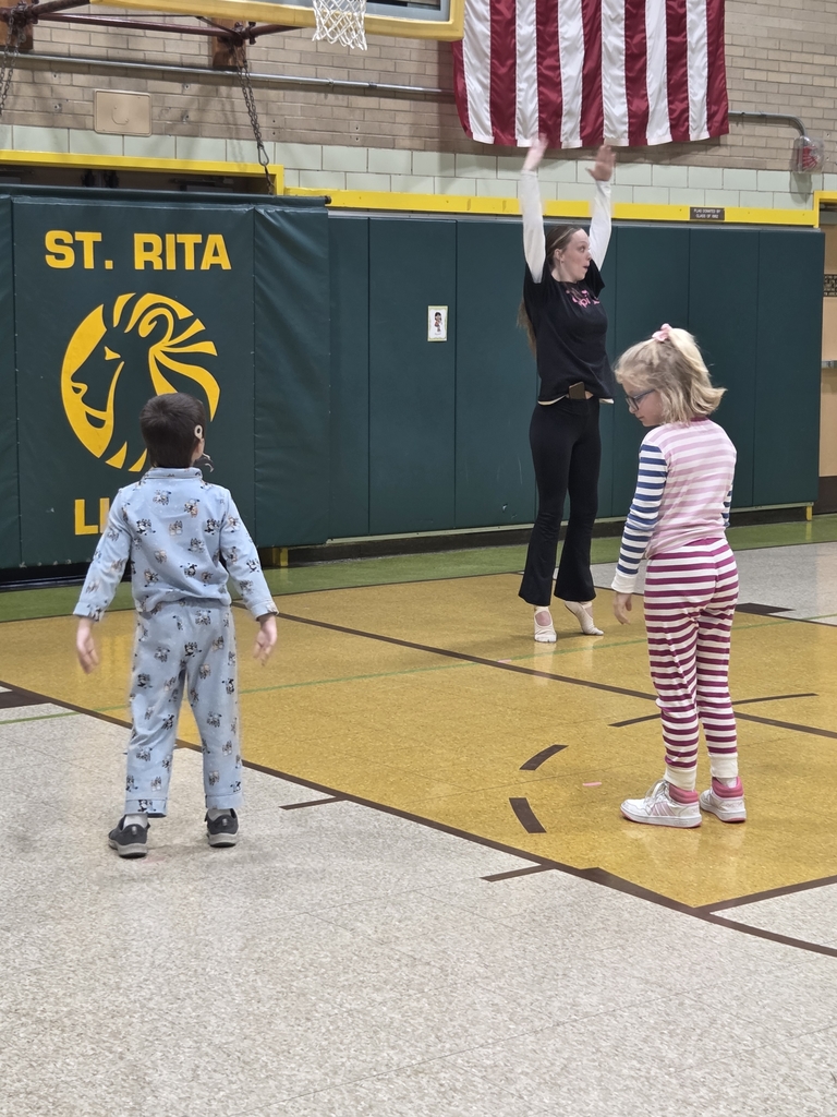 In the gymnasium 2 students are watching the dance teacher show off how to dance on there toes.