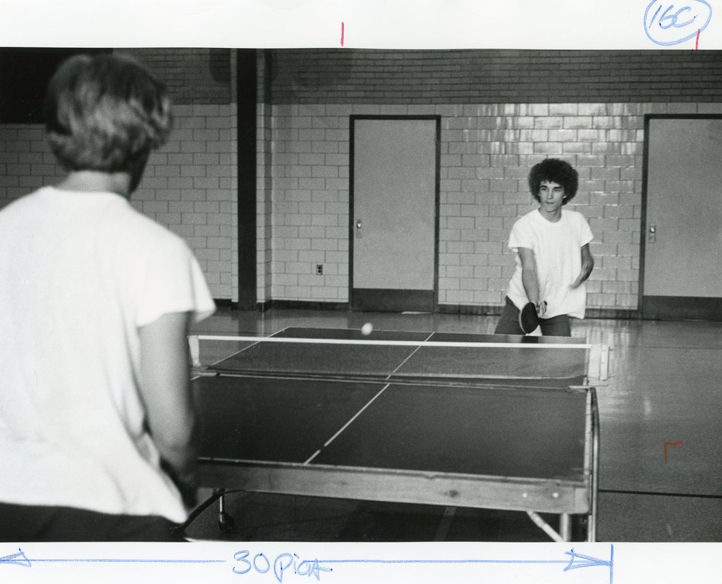 female and male students are playing ping pong
