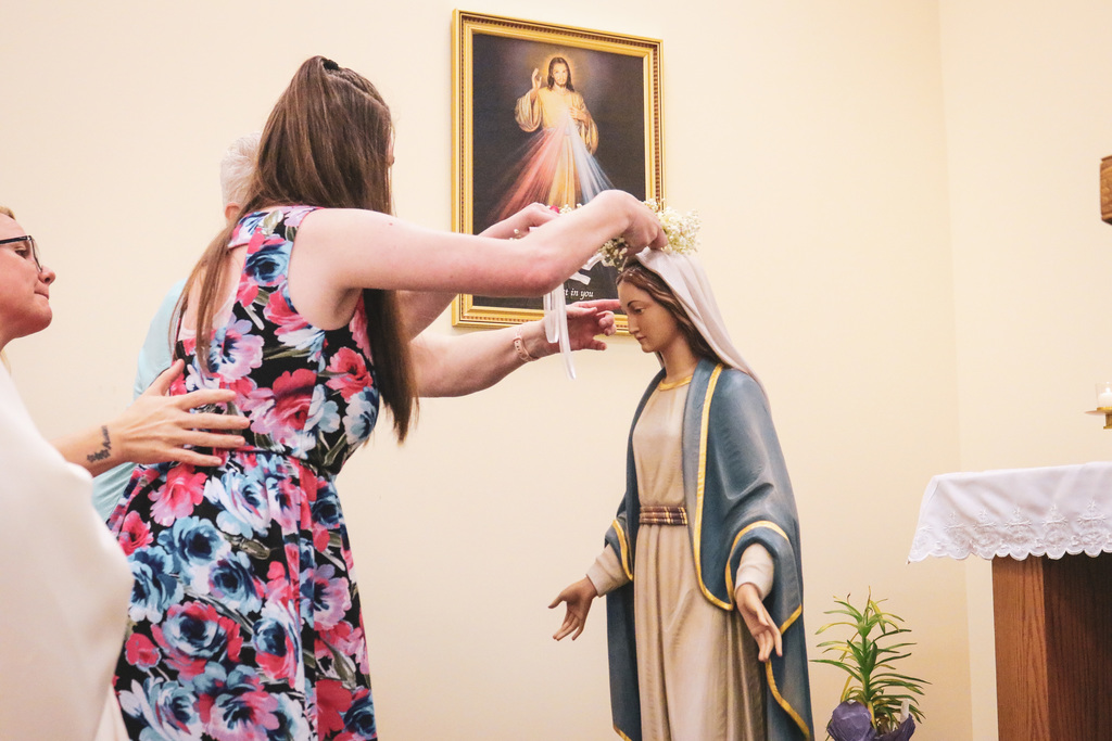 a girl student putting flowers crown on Mary