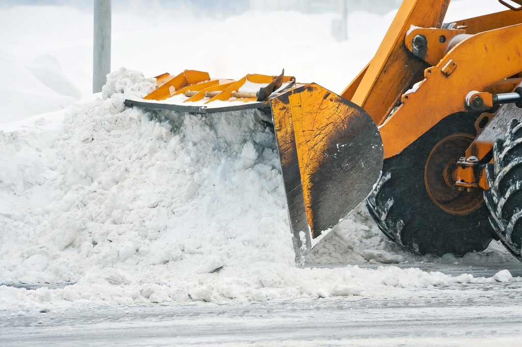 Front-end loader clearing snow from an icy street.