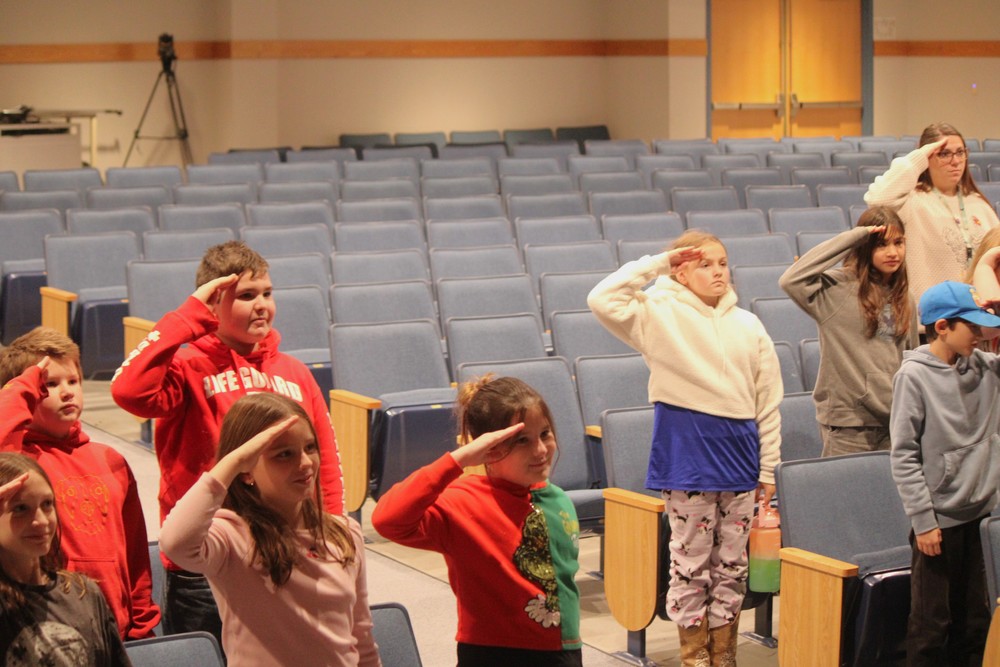 Students and teachers saluting veterans during presentation