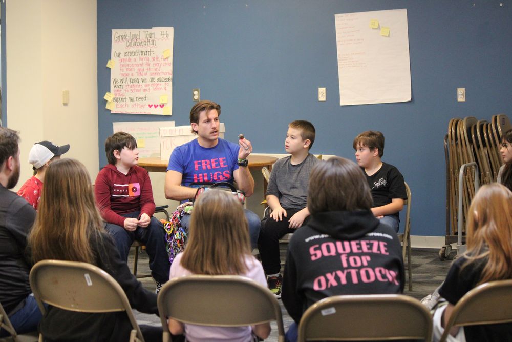 Students in a circle listening to an adult