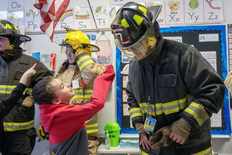 Male high school student in firefighter gear with a male elementary student